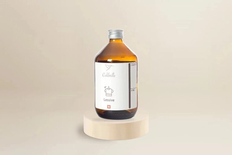 Bouteille en verre ambré vide Colibrille Lessive, avec étiquette, sur un socle en bois